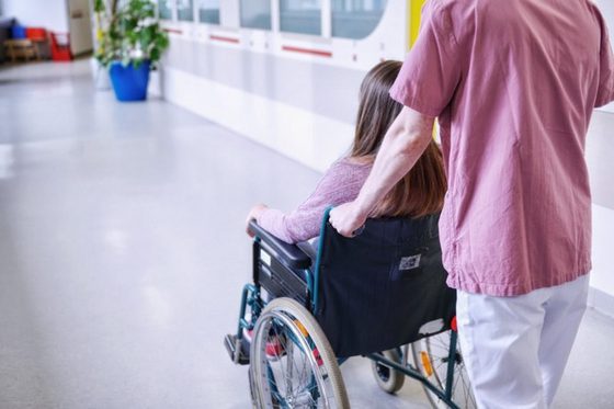 Krankenpfleger mit einer Patientin im Rollstuhl