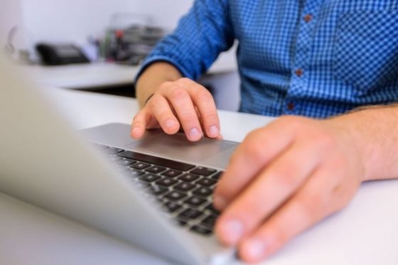 Ein Mann sitzt in einem Büro und arbeitet am Laptop.