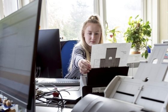 Eine junge Frau im Büro scannt ein Dokument ein.